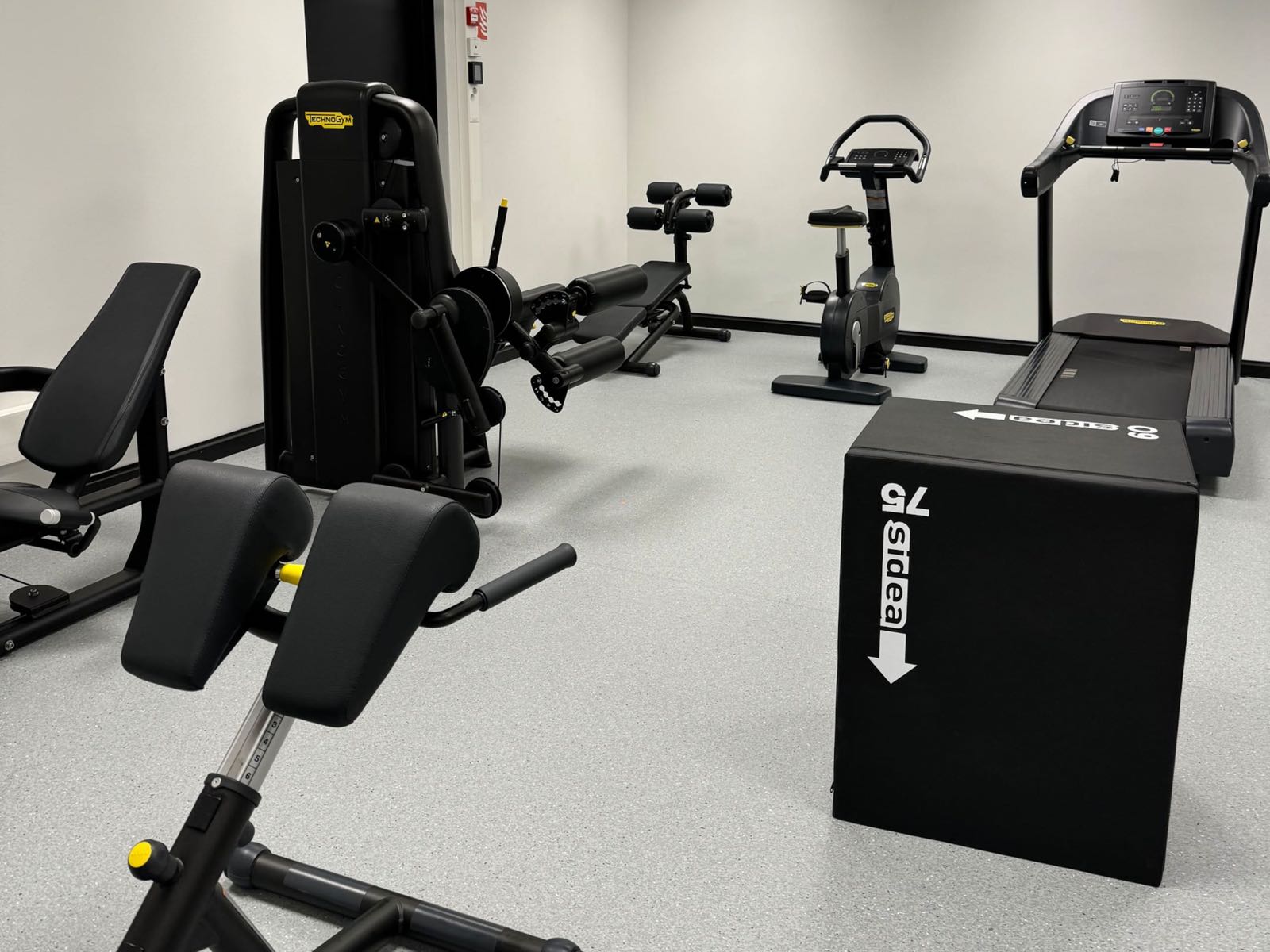 A treadmill, a stationary bike and weight-stack strength machines in the building's gym