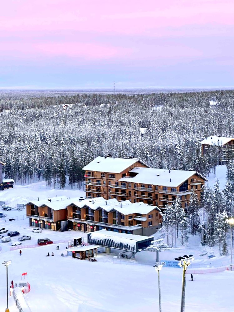 The Cranberry building from above, with a lift station in front and snowy forest behind, under a pink sky